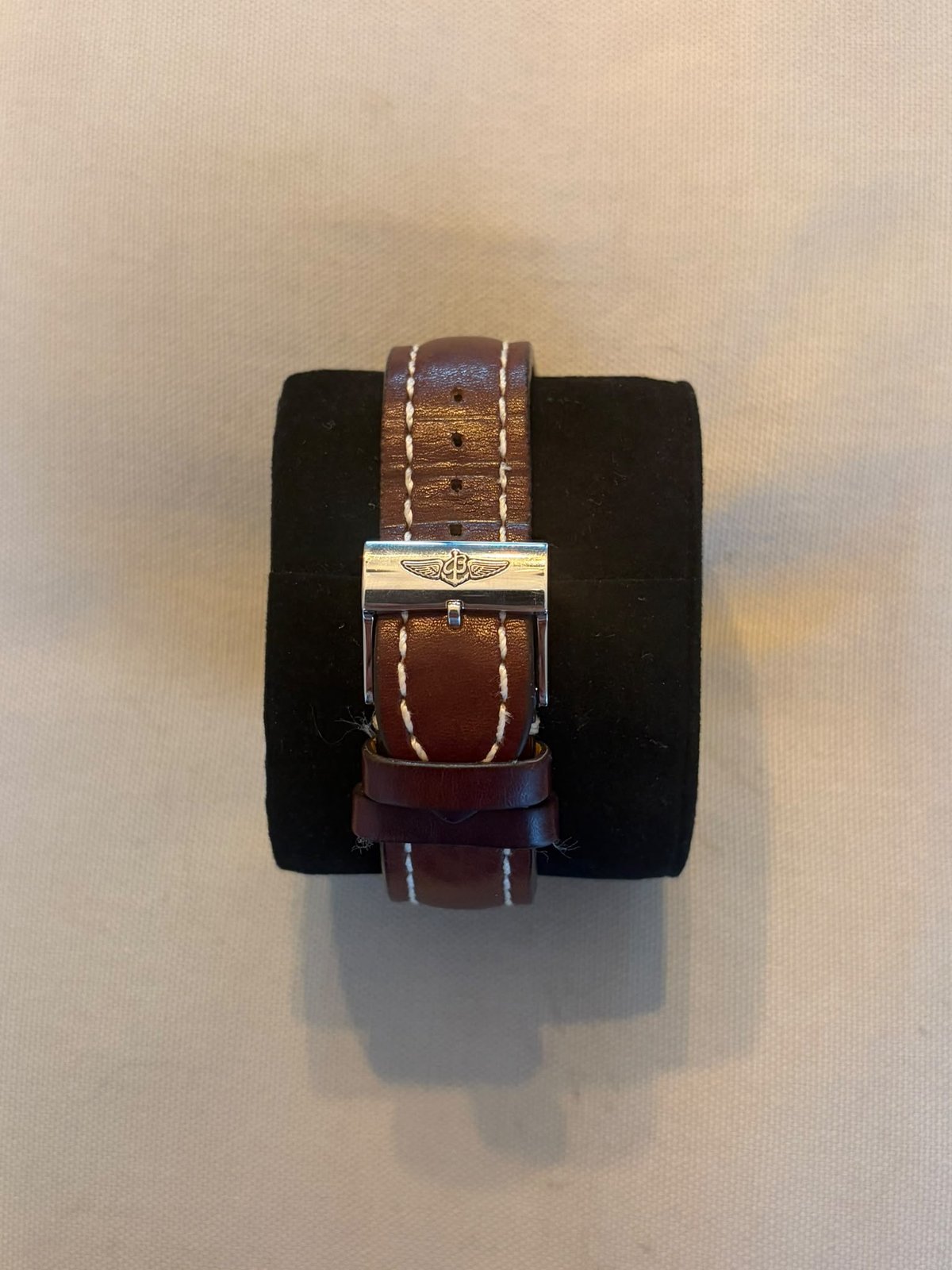 Breitling leather strap with metal buckle displayed on a black cushioned watch block
